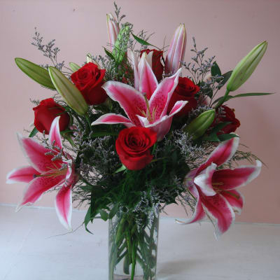 Bouquet of pink lilies and red roses in a clear glass vase
