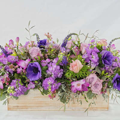 Purple and pink floral arrangement in a wooden box