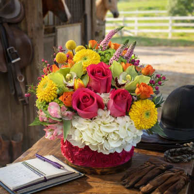 Colorful mixed flower arrangement in a round box on a wooden table