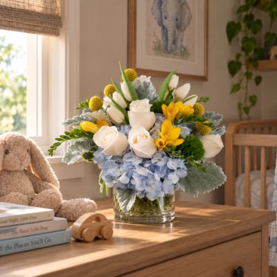 Bouquet of white roses, blue hydrangeas, and yellow flowers in a glass vase