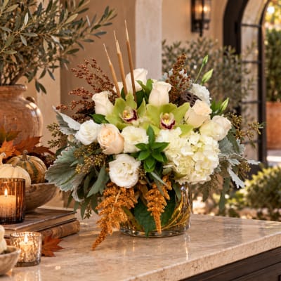 Cream and green floral arrangement in a glass vase with candles