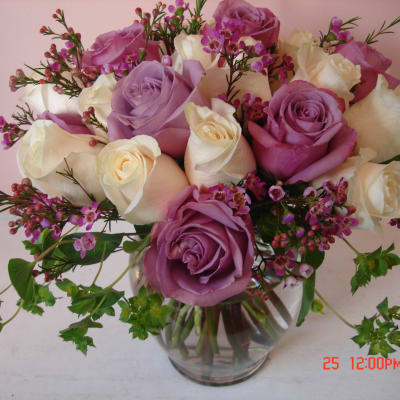 Bouquet of pink, lavender, and white roses in a clear glass vase