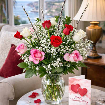 Bouquet of red, pink, and white roses in a glass vase with a Valentine card