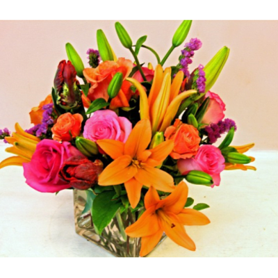 Bright mixed bouquet with orange lilies and pink roses in a glass vase