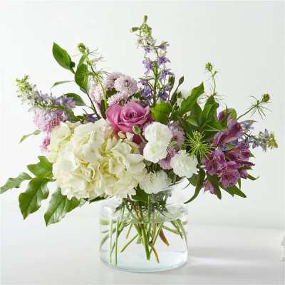 Mixed white and purple flower arrangement in a clear glass vase.