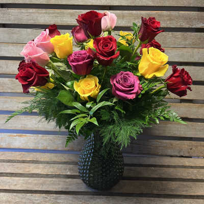 Mixed roses in red, pink, and yellow arranged in a dark vase