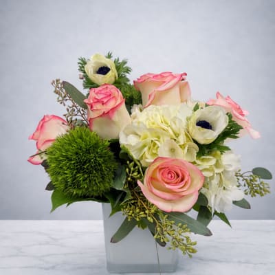 Pink-edged roses and white blooms in a square glass vase