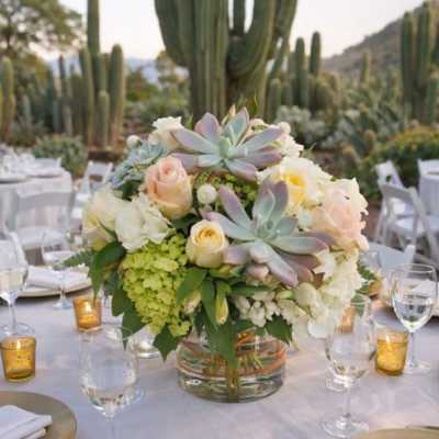 Low floral centerpiece in a glass vase on a set table outdoors
