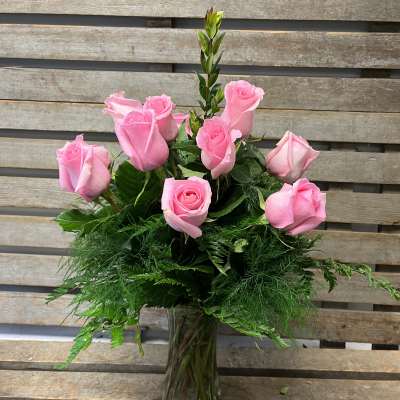Pink roses arranged in a clear glass vase with lush greenery