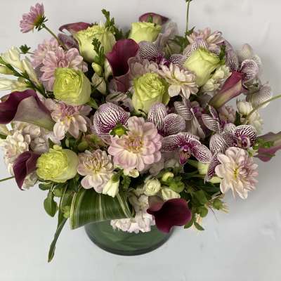 Mixed bouquet of pale pink and green flowers in a glass vase