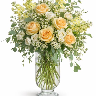 Peach and white roses in a clear glass vase with airy white filler flowers