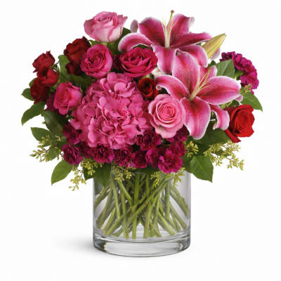 Pink lilies and roses arranged in a clear glass vase