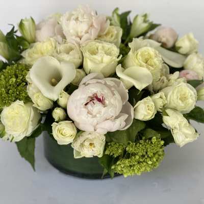 Cream and pale pink floral arrangement in a dark vase