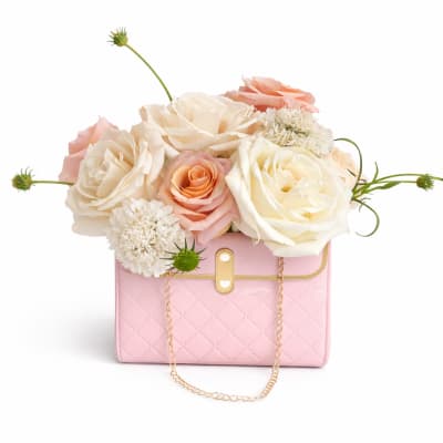 Pink handbag with cream and peach roses arranged on top