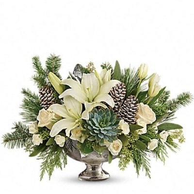 White lilies and succulents arranged in a silver pedestal bowl