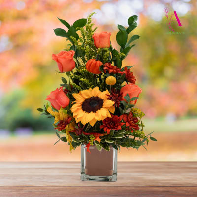 Autumn bouquet with sunflowers, orange roses, and a glass vase