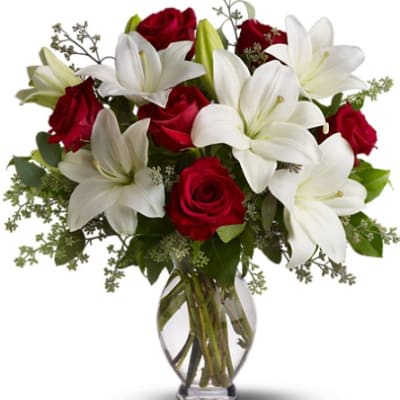 Bouquet of red roses and white lilies in a clear glass vase