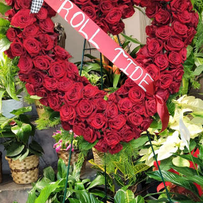 Heart-shaped red rose wreath with a pink ribbon sash
