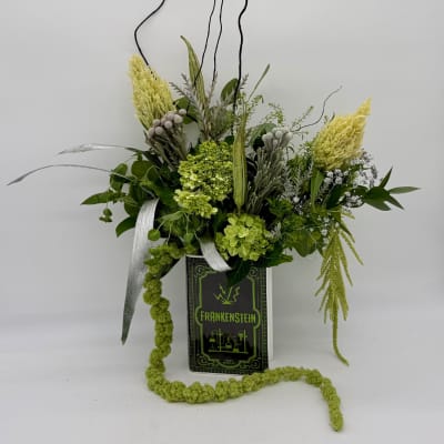 Green floral arrangement in a Frankenstein book-shaped container