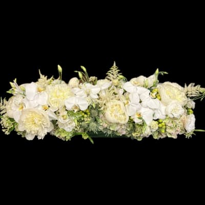 Long white floral arrangement with orchids and pale cream blooms