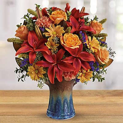 Mixed bouquet of red and orange flowers in a blue vase