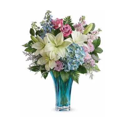 Bouquet of lilies, roses, and hydrangeas in a blue glass vase