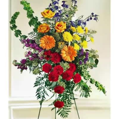 Tall standing spray on an easel with bright red, yellow, orange, and purple flowers.