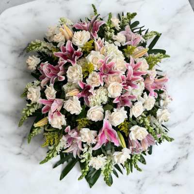 Pink lilies and white roses arranged in a round bouquet