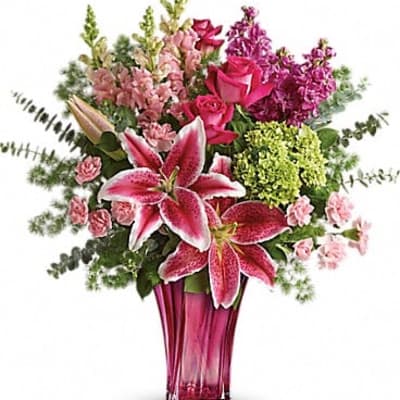 Pink lilies and roses in a tall magenta vase
