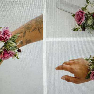 Wrist corsage with pink roses, white flowers, and greenery on a white ribbon band