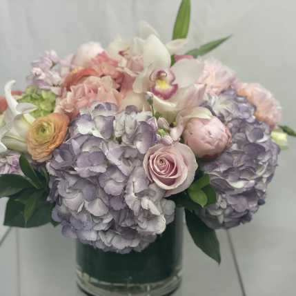 Pastel bouquet of hydrangeas, roses, and orchids in a glass vase