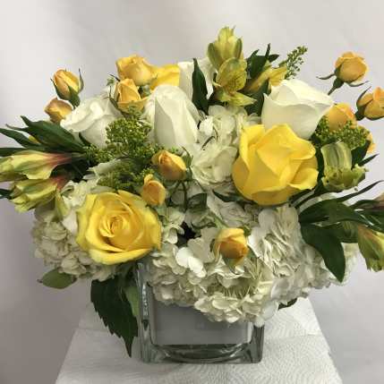 Yellow and white rose bouquet in a clear square vase