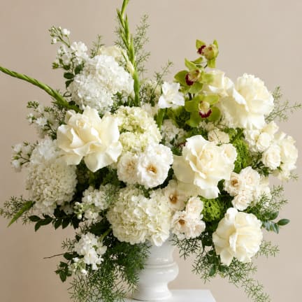 White floral arrangement in a white vase with green accents