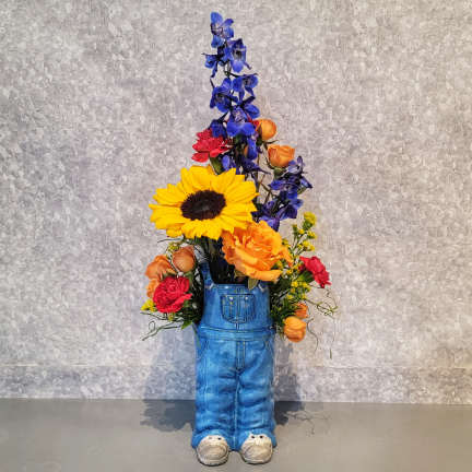 Mixed flowers arranged in a blue denim overalls planter.