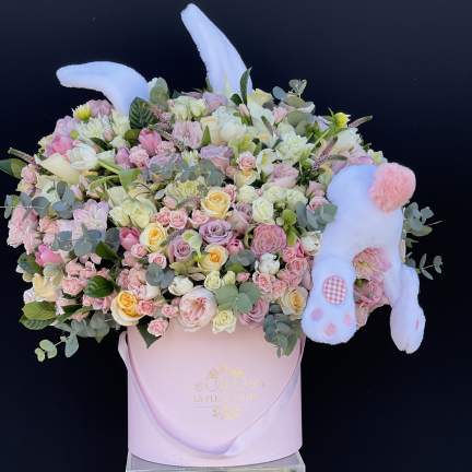 Pastel flower arrangement in a pink box with a plush bunny