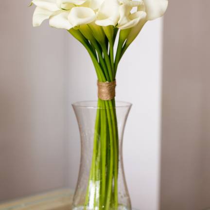 Tall bouquet of white calla lilies in a clear glass vase