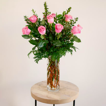 Pink roses arranged in a clear glass vase on a round table