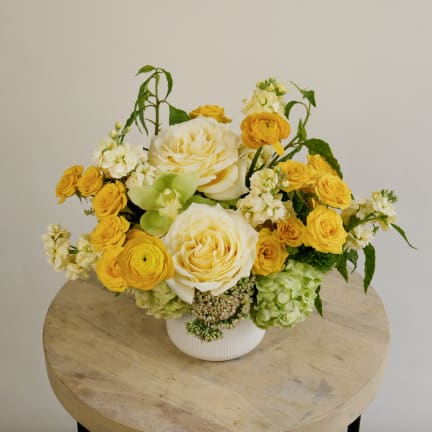 Yellow and white floral arrangement in a white vase