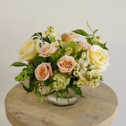 Bouquet of peach and cream roses in a clear glass vase