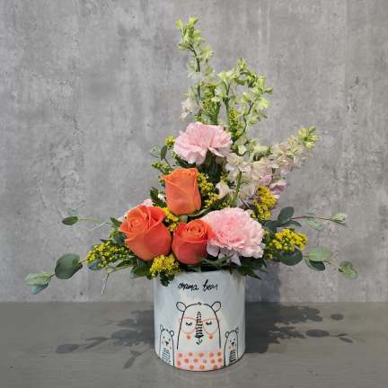 Pink and orange floral arrangement in a bear-printed ceramic container