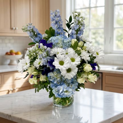 Blue and white mixed flower arrangement in a clear glass vase
