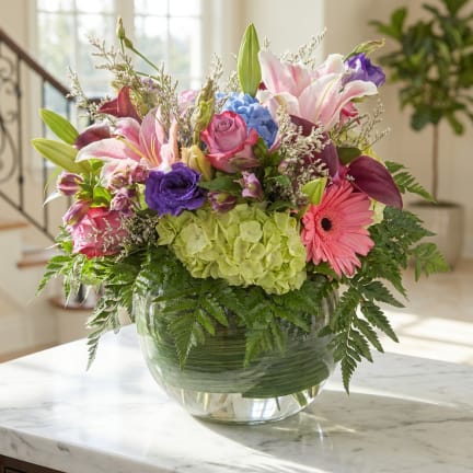 Mixed bouquet with lilies, roses, hydrangea, and a gerbera daisy in a glass vase