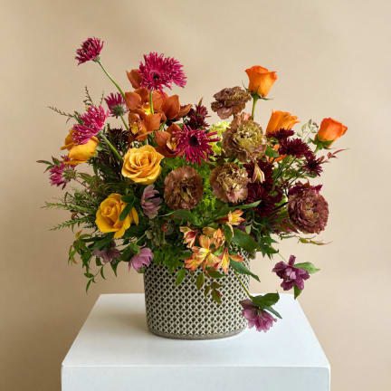 Mixed bouquet in a patterned metal vase with orange and purple blooms