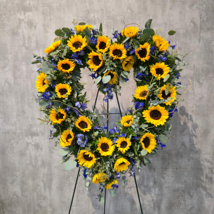 Heart-shaped sunflower wreath on a stand with blue flowers