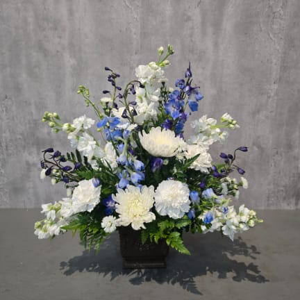 White and blue floral arrangement in a dark square vase
