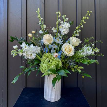 Tall white and green floral arrangement in a ribbed vase