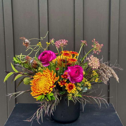 Colorful floral arrangement in a black vase with magenta and orange blooms