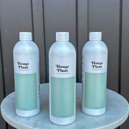 Three bottles of house plant fertilizer on a round marble table