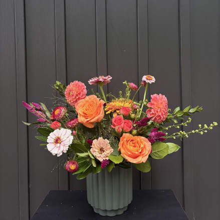Mixed bouquet of orange and pink flowers in a ribbed vase