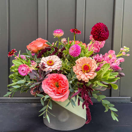 Low arrangement of pink and peach mixed flowers in a round ceramic vase